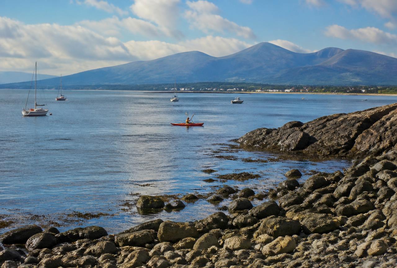 Sailing boats and a kayak on Carlingford Lough with the Mourne Mountains beyond